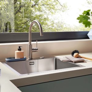 Moderne Naber Küchenarmatur mit Edelstahl-Spüle und Vorfensterlösung – elegantes Design trifft auf maximale Funktionalität für komfortables Arbeiten mit Blick ins Grüne.