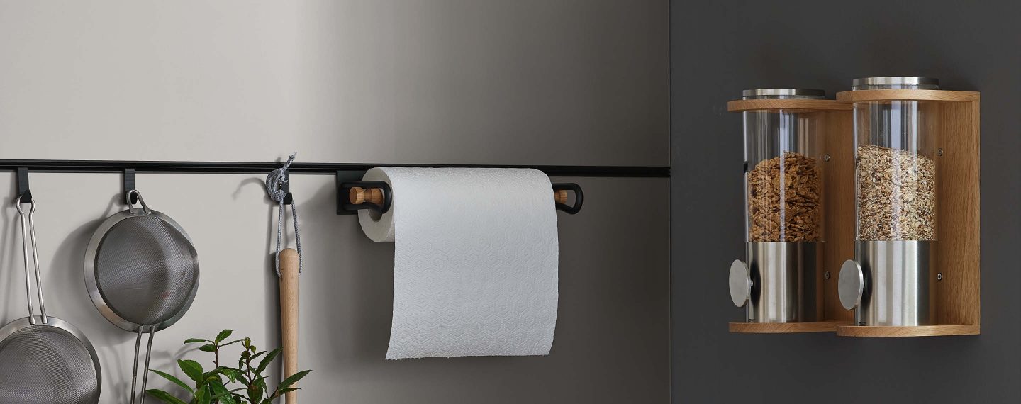 Praktische Küchenreling mit integrierten Aufhängelösungen für Küchenutensilien und stilvollem Papierrollenhalter, kombiniert mit dekorativen Vorratsbehältern für eine funktionale und aufgeräumte Küchenorganisation