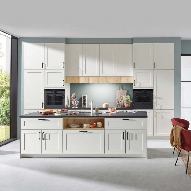 Zeitlose Landhausküche in Weiß mit klaren Linien, dunkler Arbeitsplatte und harmonischen Holzdetails für ein helles, freundliches Wohngefühl